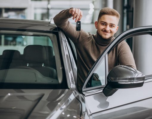 Young handsome man choosing a car in a car showroom